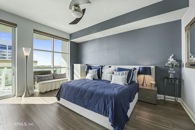 bedroom with a textured ceiling, baseboards, and dark wood-type flooring