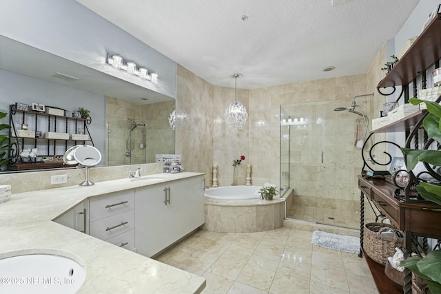 full bath featuring a stall shower, vanity, a textured ceiling, and a bath