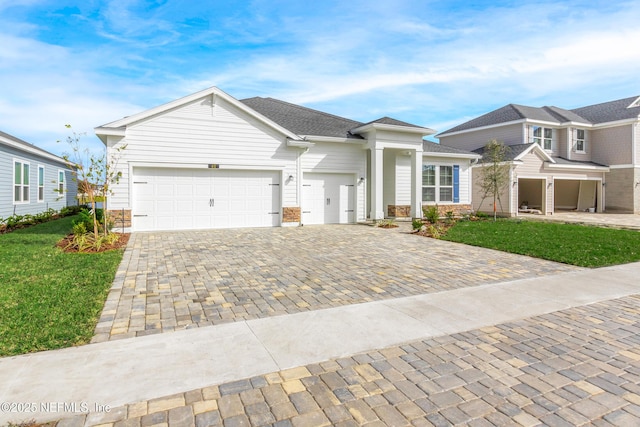 view of front of home with roof with shingles, a front lawn, decorative driveway, and an attached garage