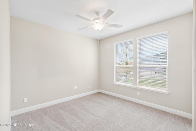 empty room with light carpet, a textured ceiling, baseboards, and a ceiling fan