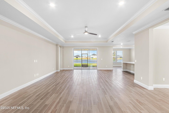 unfurnished living room with a raised ceiling, light wood-style flooring, ornamental molding, ceiling fan, and baseboards