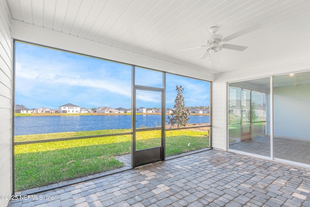 unfurnished sunroom with a water view, a residential view, and a ceiling fan