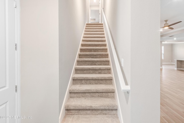 stairs with baseboards, crown molding, a ceiling fan, and wood finished floors