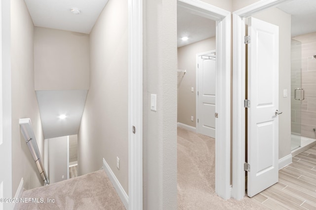 hallway featuring baseboards, an upstairs landing, and wood tiled floor