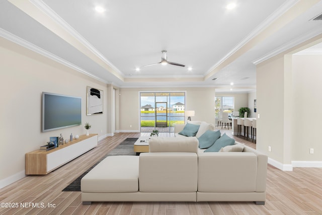 living area featuring a tray ceiling, crown molding, visible vents, wood tiled floor, and baseboards