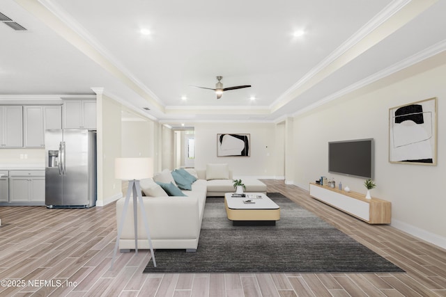 living room featuring wood finish floors, a raised ceiling, visible vents, and crown molding