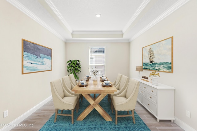 dining space with ornamental molding, wood finish floors, a raised ceiling, and baseboards