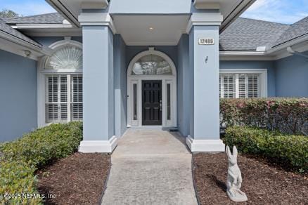 doorway to property with a shingled roof and stucco siding