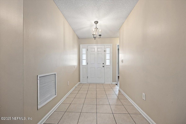 entrance foyer with baseboards, visible vents, a textured ceiling, a notable chandelier, and light tile patterned flooring