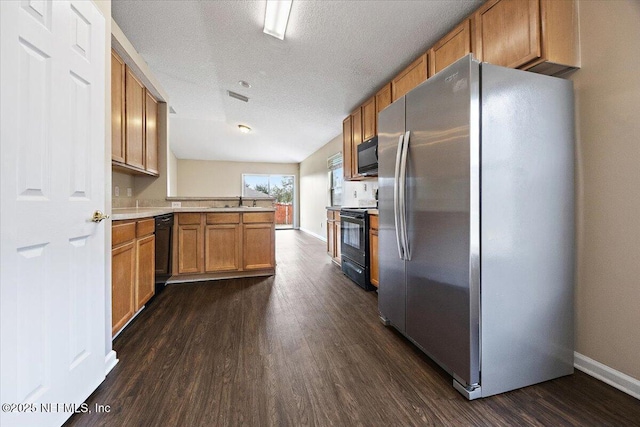 kitchen with a peninsula, black appliances, dark wood-style floors, and light countertops