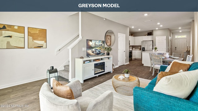 living area featuring baseboards, wood finished floors, stairs, a fireplace, and recessed lighting