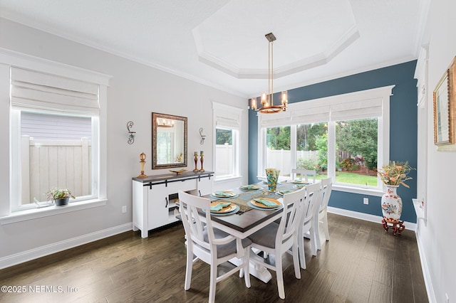 dining area with dark wood-style floors, a tray ceiling, a chandelier, and ornamental molding