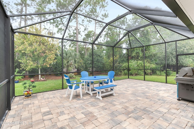 view of patio featuring outdoor dining area, glass enclosure, and grilling area