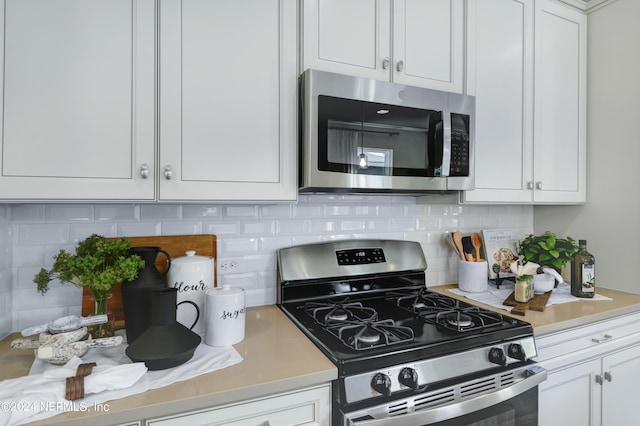 kitchen featuring stainless steel appliances, backsplash, light countertops, and white cabinets