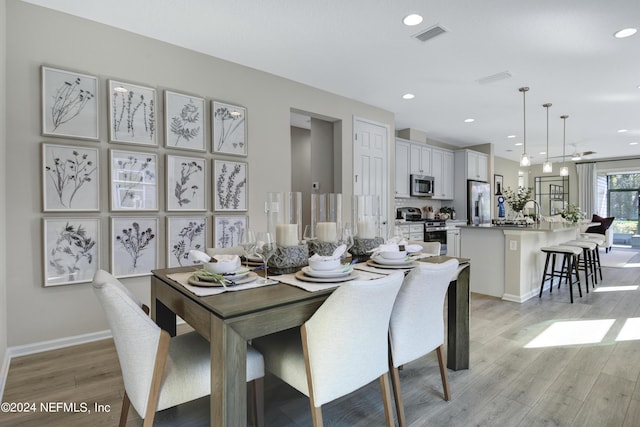 dining area with baseboards, light wood-type flooring, visible vents, and recessed lighting