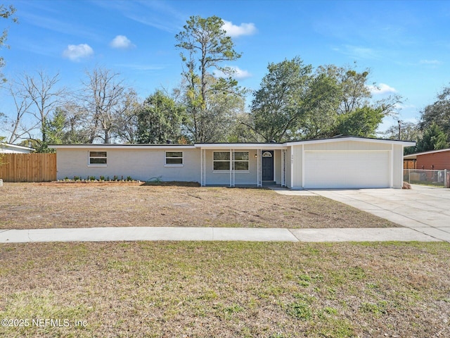 ranch-style home featuring a garage, concrete driveway, a front lawn, and fence