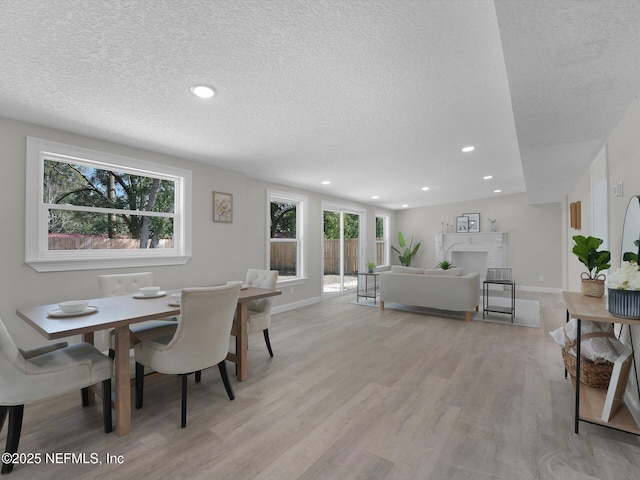 dining space featuring light wood-type flooring, a fireplace, baseboards, and recessed lighting