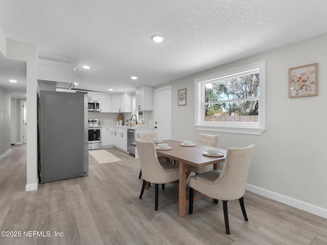 dining room featuring a textured ceiling, recessed lighting, light wood-type flooring, and baseboards