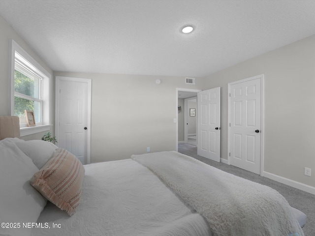 carpeted bedroom with a textured ceiling and baseboards