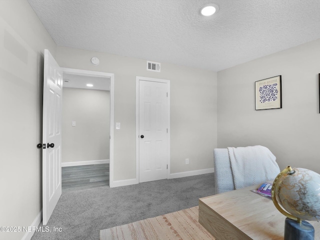 sitting room featuring carpet, visible vents, a textured ceiling, and baseboards