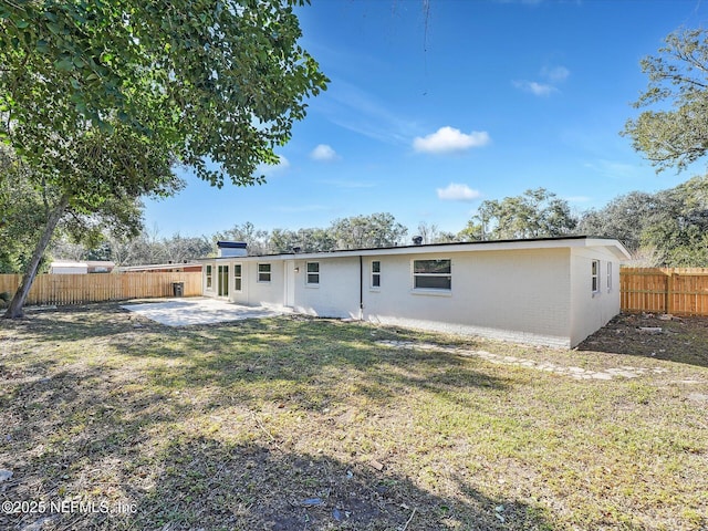 back of house with a patio area, a fenced backyard, a yard, and brick siding