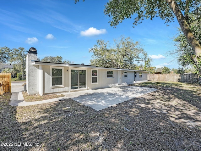 rear view of property with a patio area, a chimney, and fence