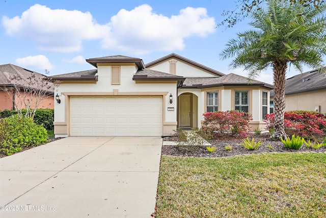 view of front of house featuring a front lawn, driveway, an attached garage, and stucco siding