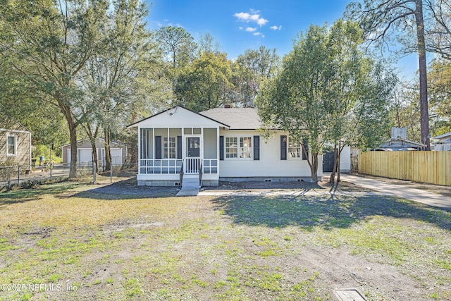 view of front of house with driveway, a front lawn, an outdoor structure, and fence