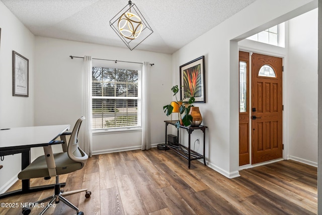 office featuring a chandelier, a textured ceiling, baseboards, and wood finished floors