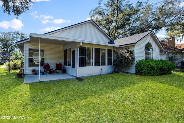 rear view of house with a sunroom, a yard, and a patio