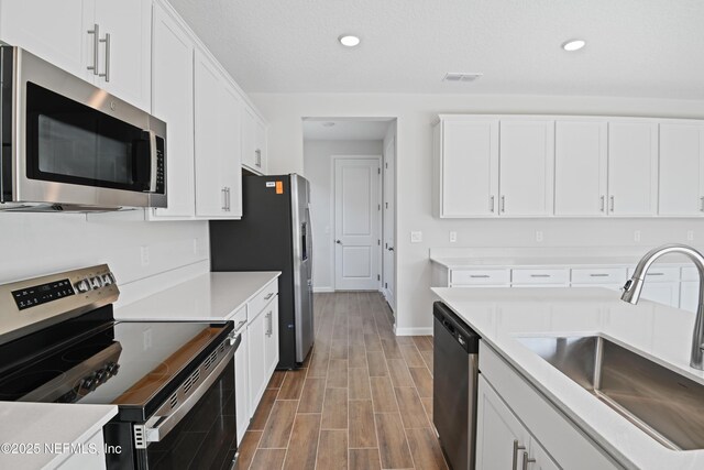 kitchen with stainless steel appliances, white cabinets, light countertops, and a sink