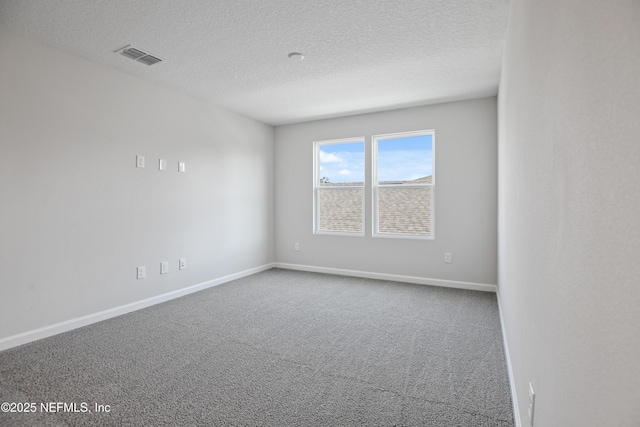 carpeted empty room with baseboards, visible vents, and a textured ceiling