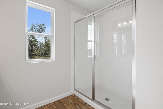 full bathroom featuring a stall shower, baseboards, and wood finish floors