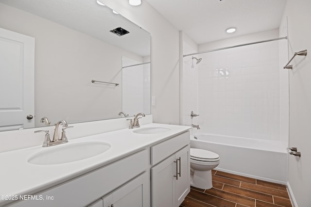 full bathroom featuring double vanity, shower / bath combination, wood tiled floor, and a sink