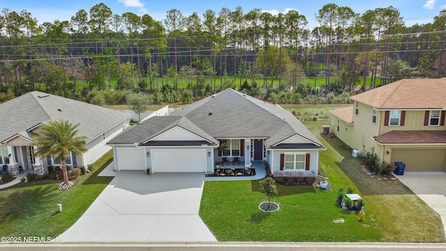 view of front facade with a garage, concrete driveway, roof with shingles, and a front yard