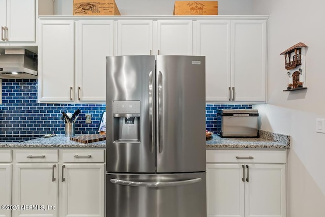 34072 Lavender Parke Dr, Fernandina Beach, FL 32034 - kitchen featuring light stone counters, white cabinetry, wall chimney range hood, and stainless steel fridge with ice dispenser
