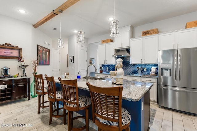 34072 Lavender Parke Dr, Fernandina Beach, FL 32034 - kitchen with under cabinet range hood, a sink, stainless steel fridge, a center island with sink, and pendant lighting