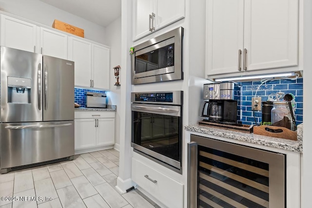 34072 Lavender Parke Dr, Fernandina Beach, FL 32034 - kitchen featuring wine cooler, light stone countertops, stainless steel appliances, white cabinetry, and decorative backsplash