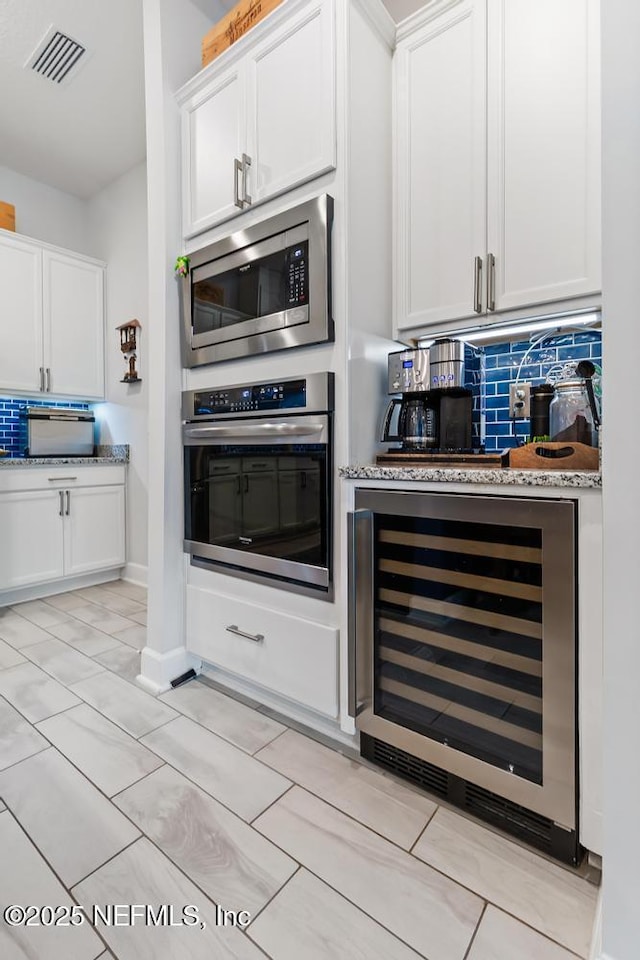 34072 Lavender Parke Dr, Fernandina Beach, FL 32034 - kitchen with stainless steel appliances, visible vents, decorative backsplash, white cabinets, and beverage cooler