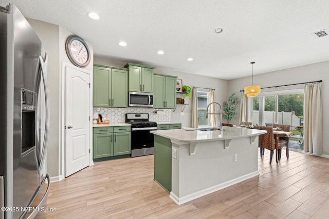 kitchen with visible vents, stainless steel appliances, light countertops, green cabinets, and a sink