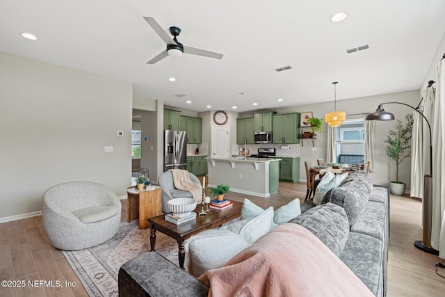 living room featuring light wood-style floors, visible vents, and plenty of natural light