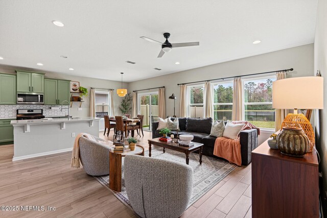 living room with light wood-type flooring, visible vents, a ceiling fan, and recessed lighting