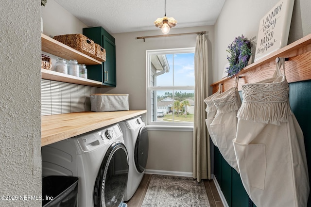 laundry room with a textured ceiling, separate washer and dryer, cabinet space, and baseboards