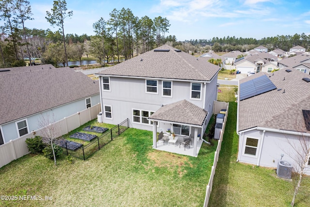 back of house with a shingled roof, central AC unit, a lawn, a fenced backyard, and a patio area