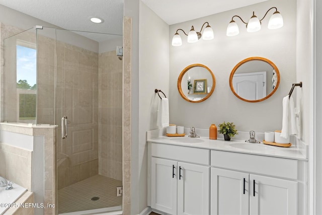 full bath with double vanity, a stall shower, tiled bath, and a sink