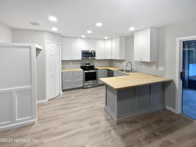 kitchen with white cabinets, appliances with stainless steel finishes, gray cabinets, and a sink