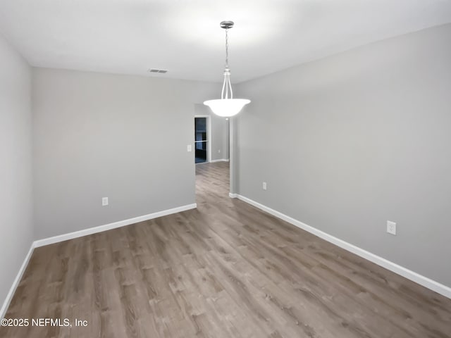 unfurnished dining area with wood finished floors, visible vents, and baseboards