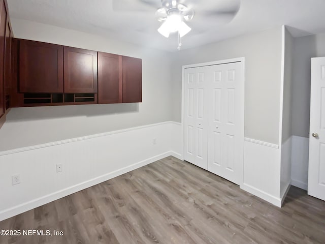 unfurnished bedroom with light wood-style floors, a closet, baseboards, and a ceiling fan