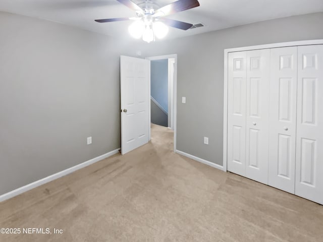 unfurnished bedroom featuring a ceiling fan, baseboards, a closet, and light colored carpet