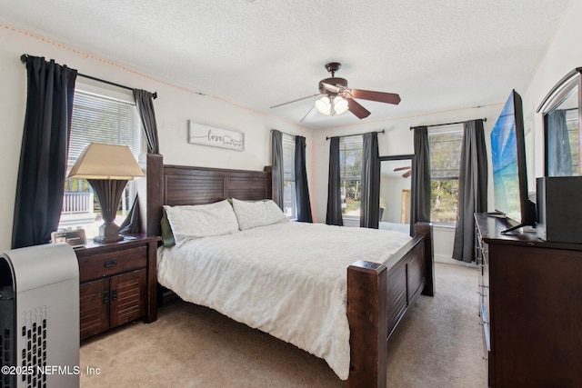 bedroom with a ceiling fan, light colored carpet, and a textured ceiling